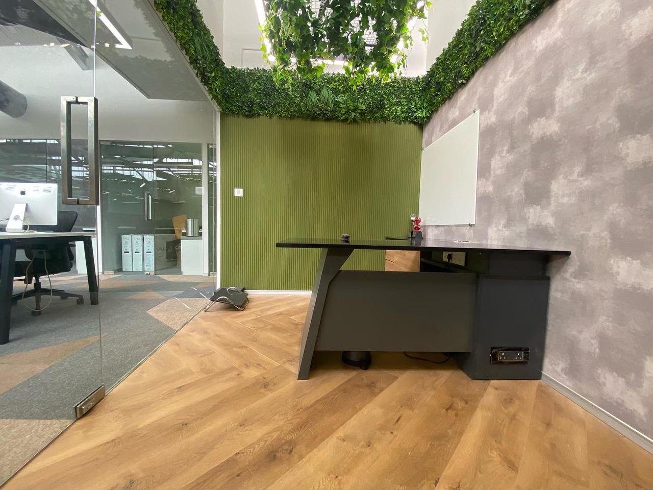 Cabin desk in dark laminate against a green slatted wall