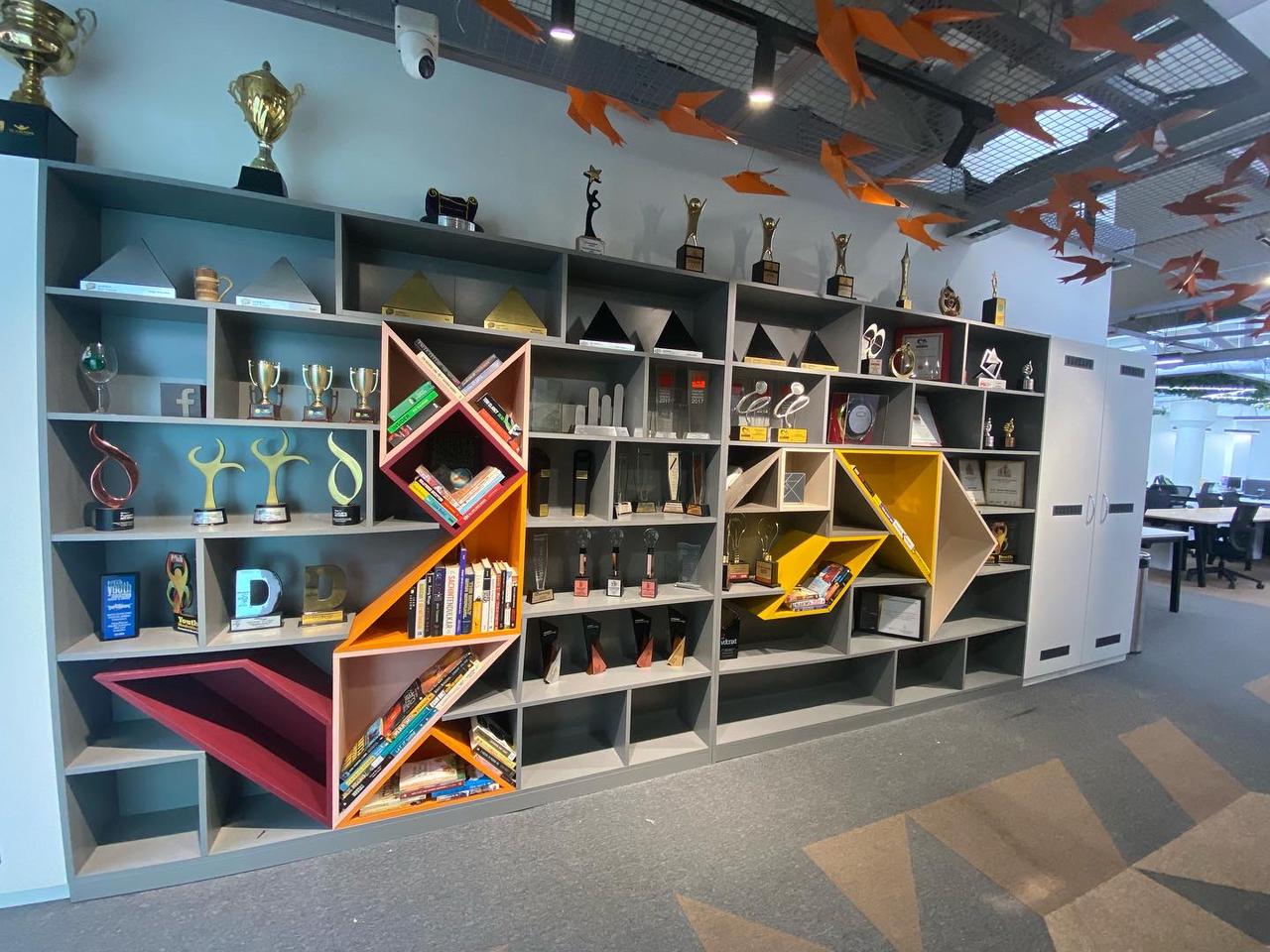 Display wall with grey shelving and coloured angled book niches