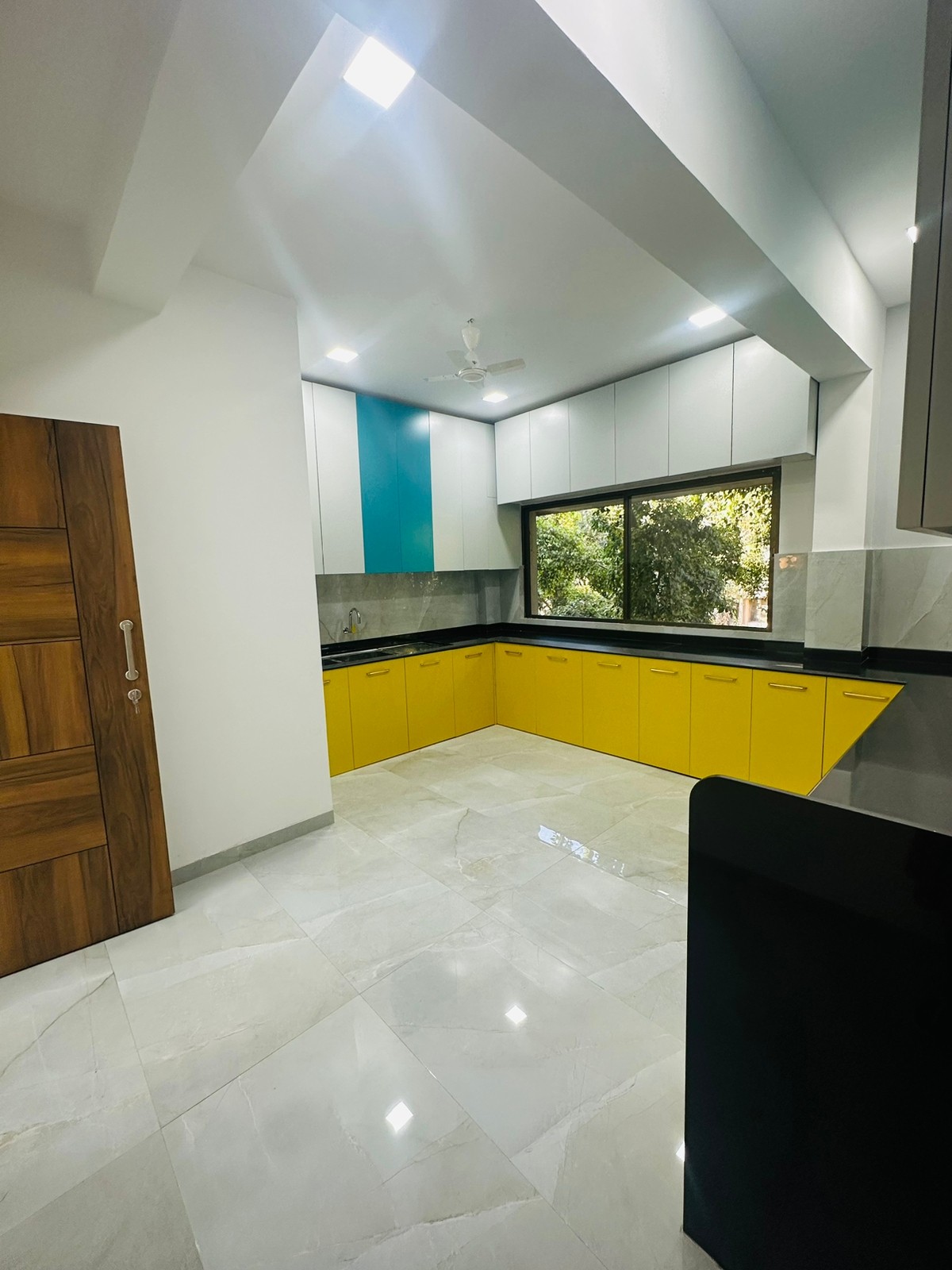 Modular kitchen with yellow base units, white wall units and a black counter