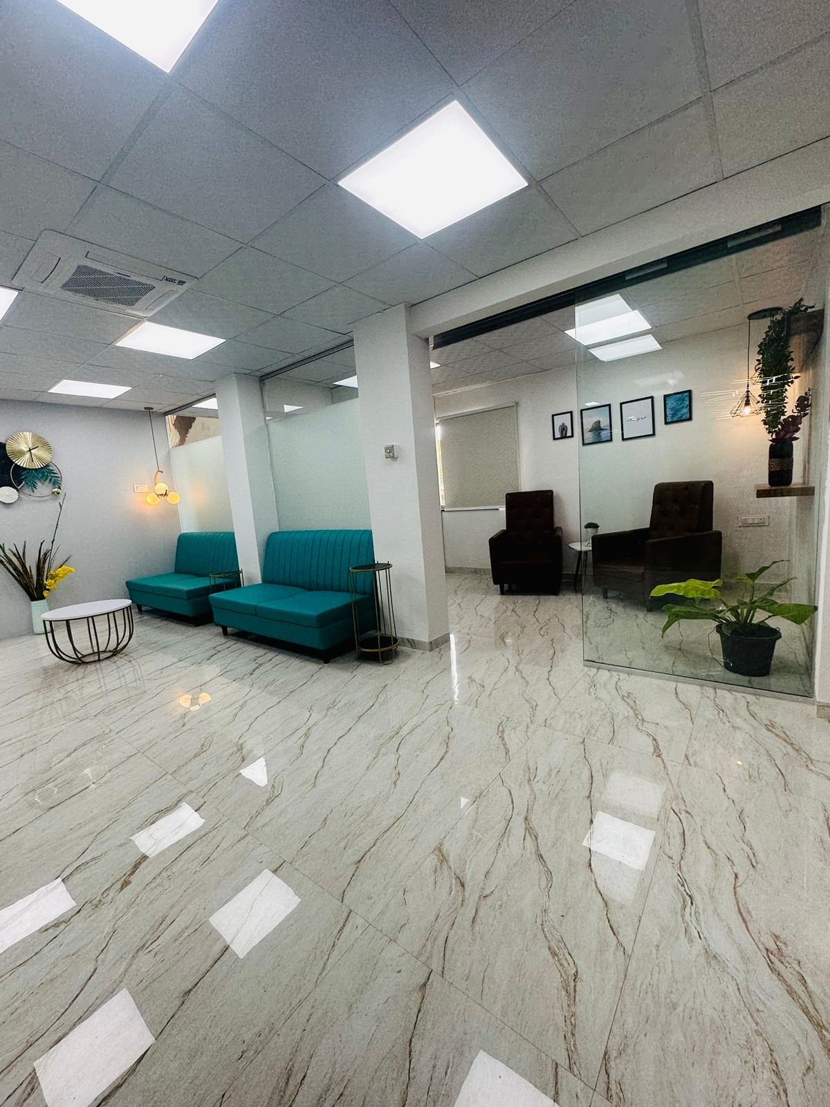 Reception area with teal sofas beside a glass-walled waiting room