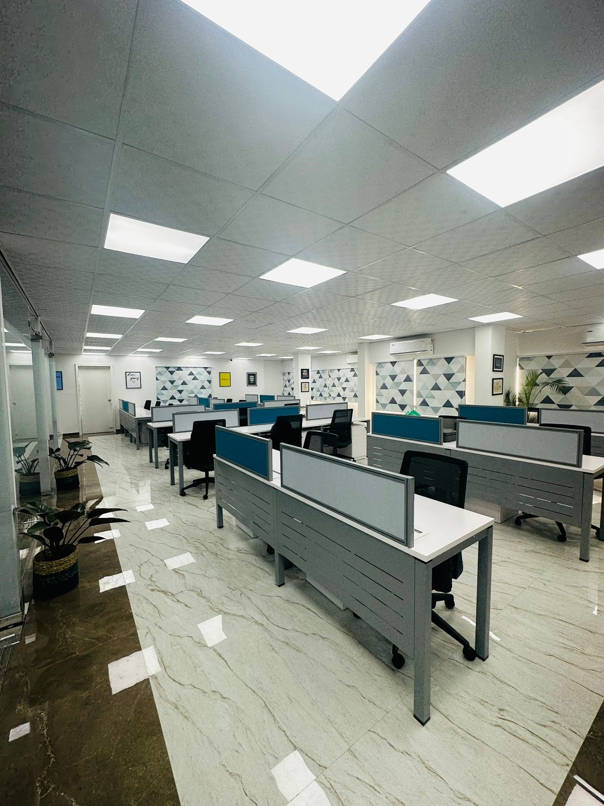 Workstations with blue and grey desk screens in a bright office with hexagon wall art